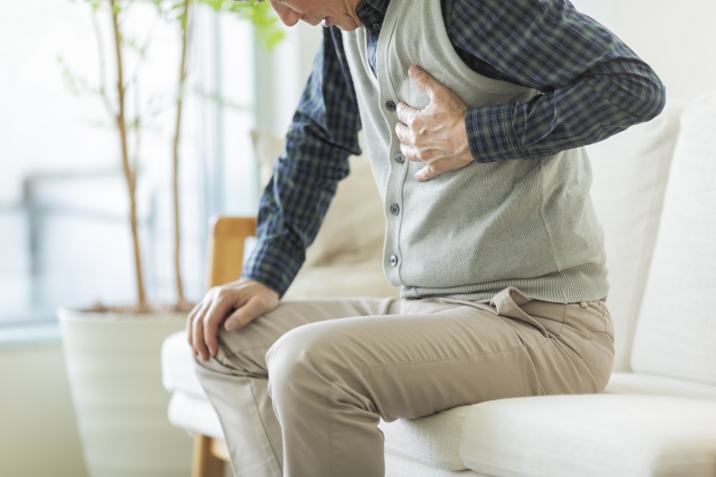 Mann stützt sich mit der Hand auf auf sein Kniw ab und hält sich mit der anderen Hand die Brust