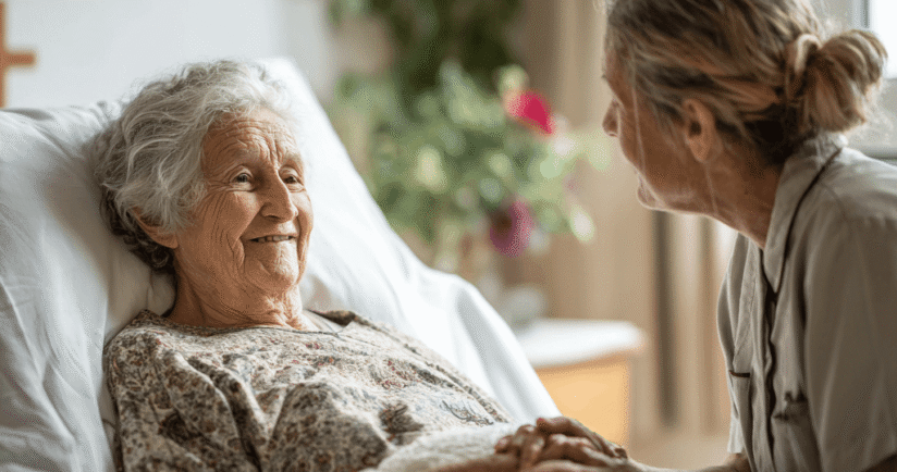 Ältere Dame im Bett, hält erleichtert die Hand der Pflegerin.