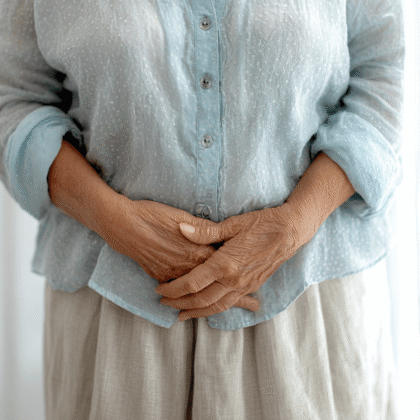 Faltige Hände vor dem Unterkörper einer älteren Dame.