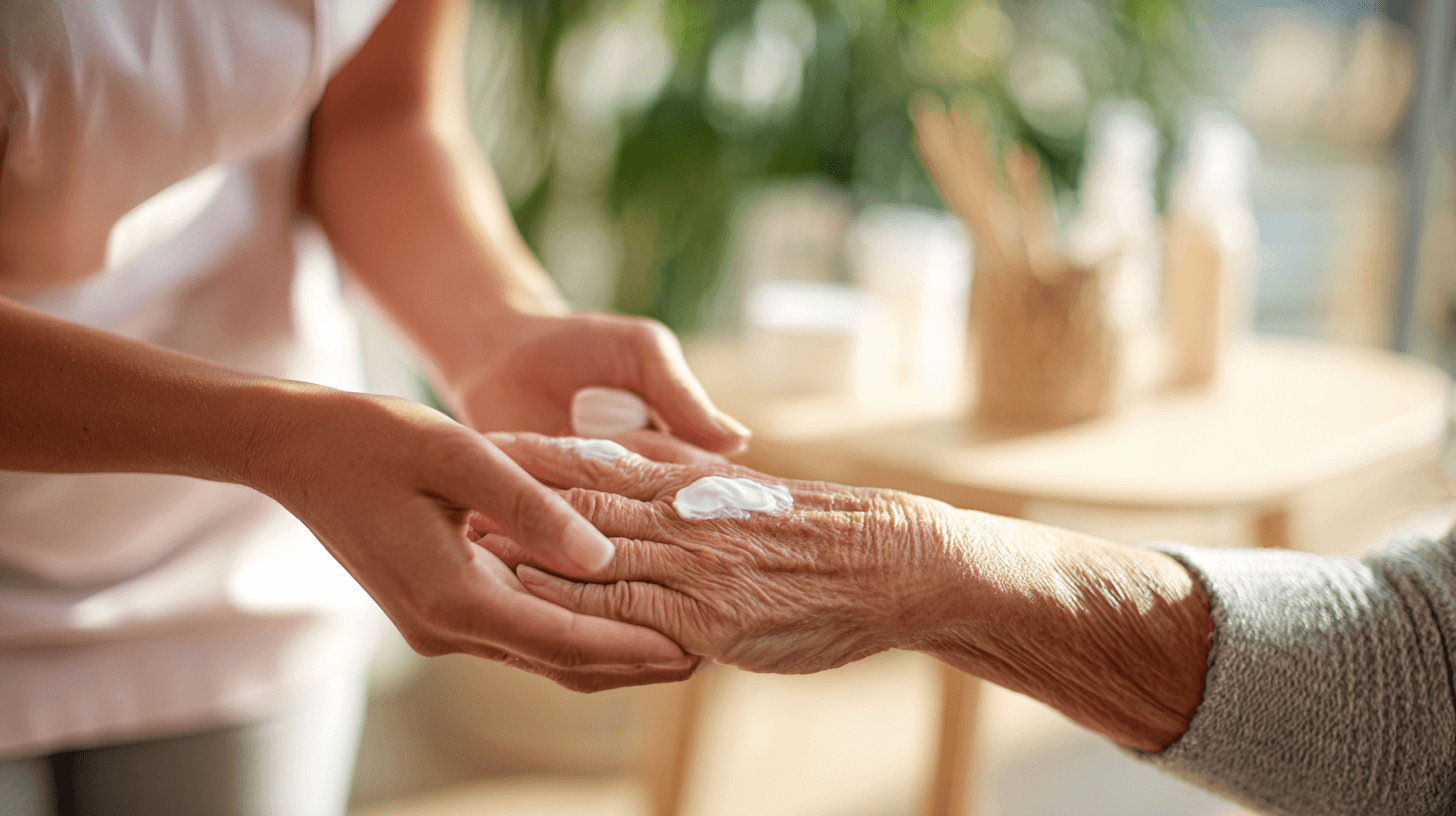 aelterer dame wird die haende eingecremt