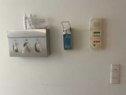 Wandmontage im Krankenhaus von Einmalhandschuhen, Desinfektionsspender und Notrufsystem.
