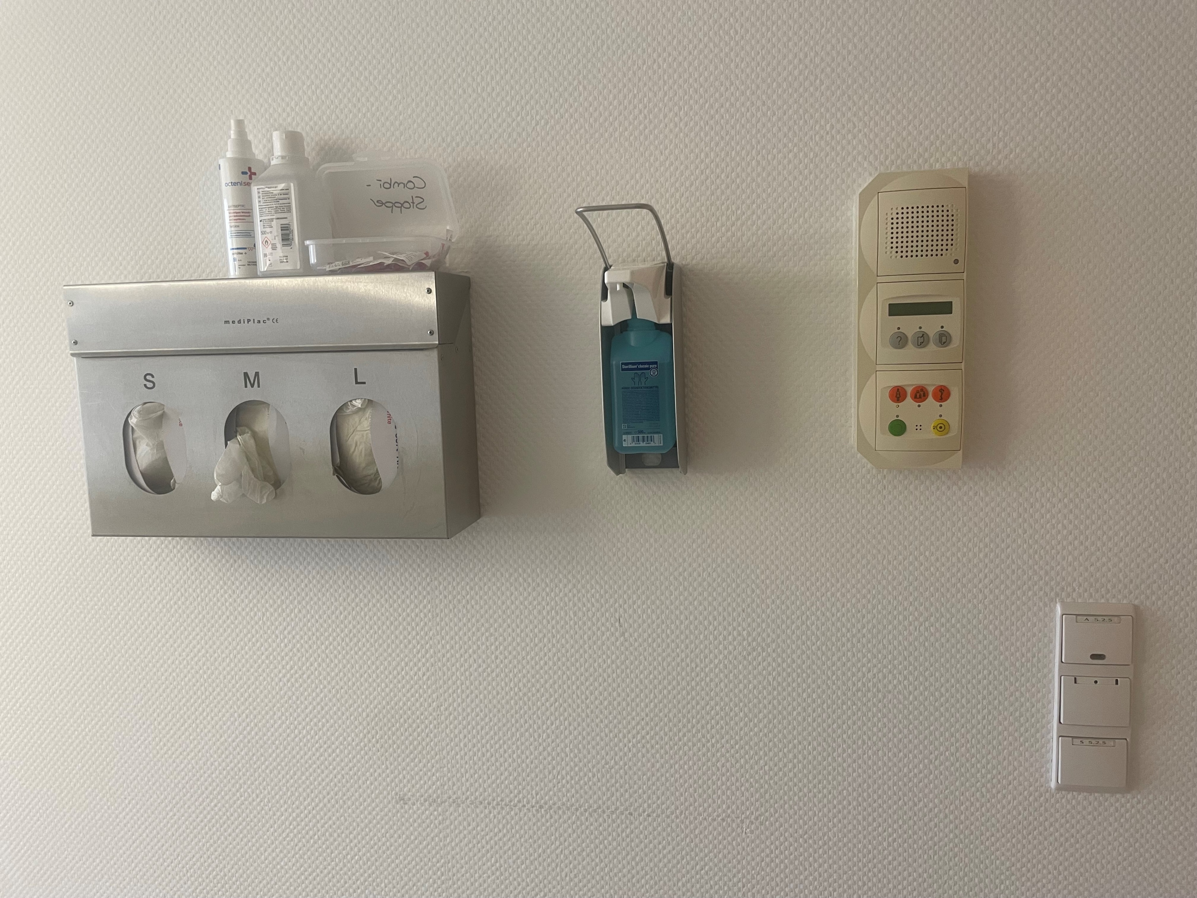 Wandmontage im Krankenhaus von Einmalhandschuhen, Desinfektionsspender und Notrufsystem.