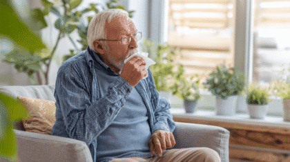 Hustender seneiorer Mann mit weißen Haaren und weißem Bart im Sessel
