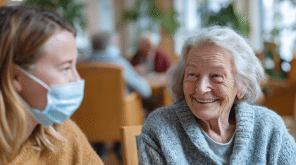 Junge Frau mit Maske. Sie hält Abstand im Sinne der Hygiene und dem Schutz der Seniorin