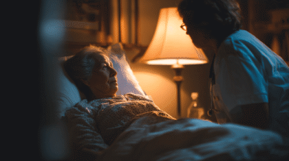 Pflegeperson bei Seniorin, die liegend im Bett ist, Symbolbild für Nachtpflege im ambulanten Bereich