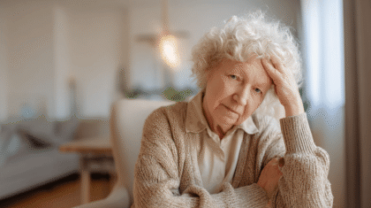 Seniorin hält sich den Kopf und ist schwindelig